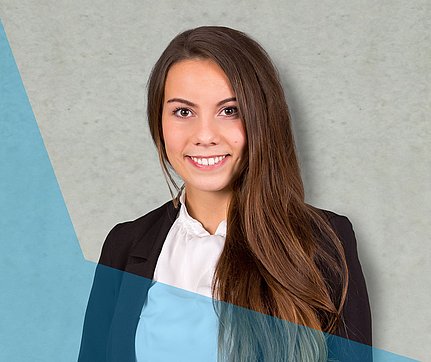 Eine lächelnde Frau in Businesskleidung mit langen braunen Haaren steht vor einem hellgrauen Hintergrund mit blauen grafischen Formen.