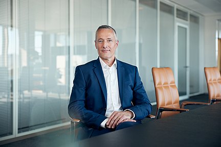 Ein Mann mit Anzug sitzt an einem Konferenztisch.
