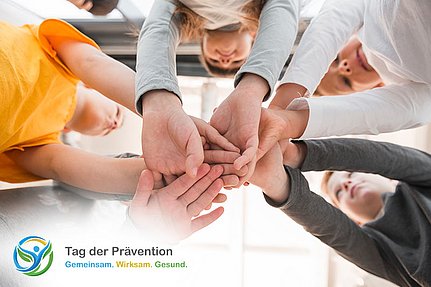 Fünf Kinder stehen im Kreis und legen ihre Hände ineinander. In der Ecke ist das Logo des „Tag der Prävention“ zu sehen.