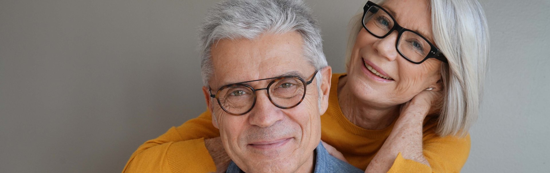 Ein älteres Paar lächelt freundlich in die Kamera.