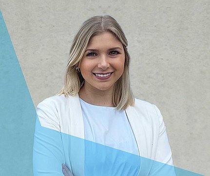 Eine lächelnde Frau mit blonden Haaren in einem weißen Blazer steht vor einem schlichten Hintergrund mit einer blauen grafischen Überlagerung.