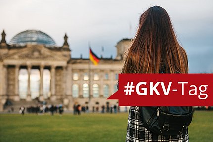 Eine Frau mit langen Haaren blickt auf den Reichstag in Berlin; darüber ist ein rotes #GKV-Tag-Banner eingeblendet.