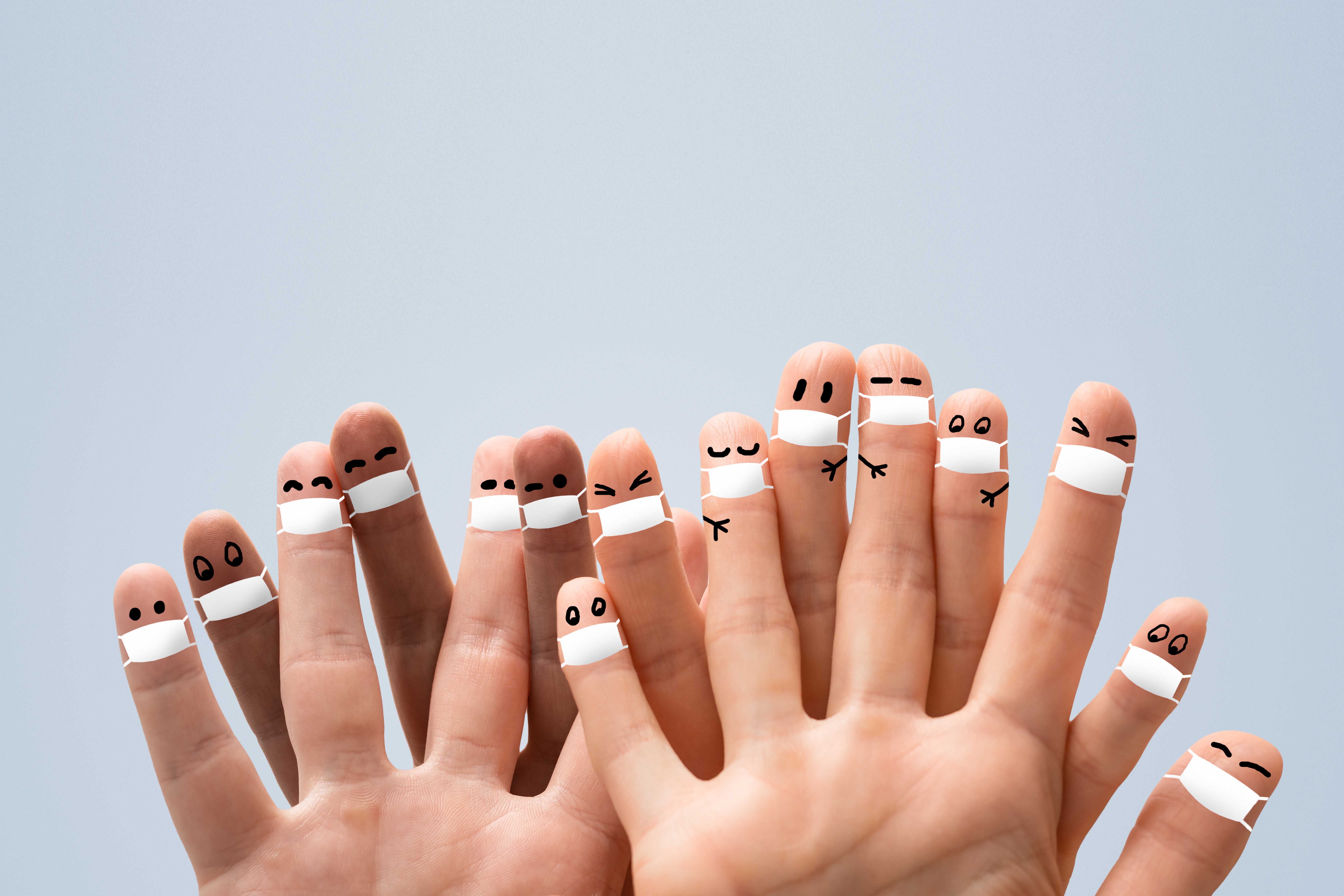 Viele Finger sind mit einem Mundschutz und Augen bemalt.